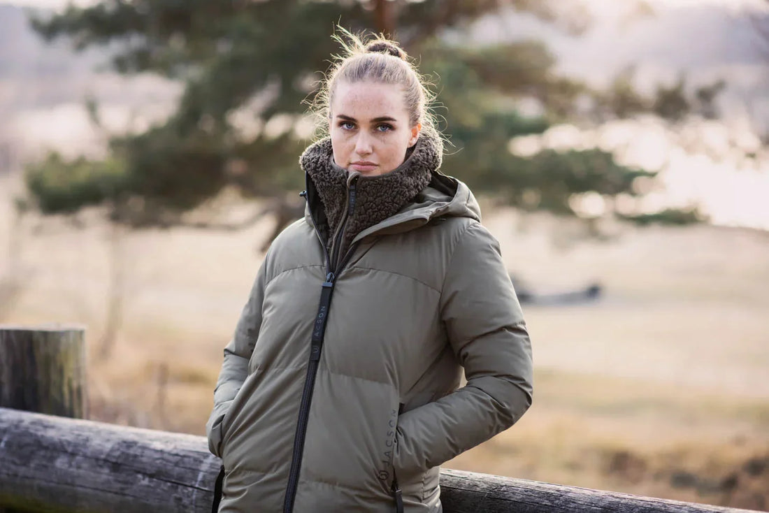 Vinterkappan Rakel, en hellång kappa med dunliknande syntetfyllning, vattenavvisande material och praktiska fickor, i färgerna svart och brungrön.